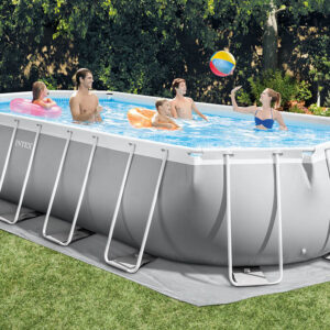 Плувен басейн Intex на открито с хора, които се наслаждават на водата и играят с топка. Лятна развлекателна дейност в задния двор, обградена от зеленина.